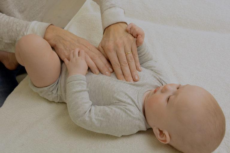 bronchiolite Bébé calme, allongé sur un lit qui se fait masser le ventre